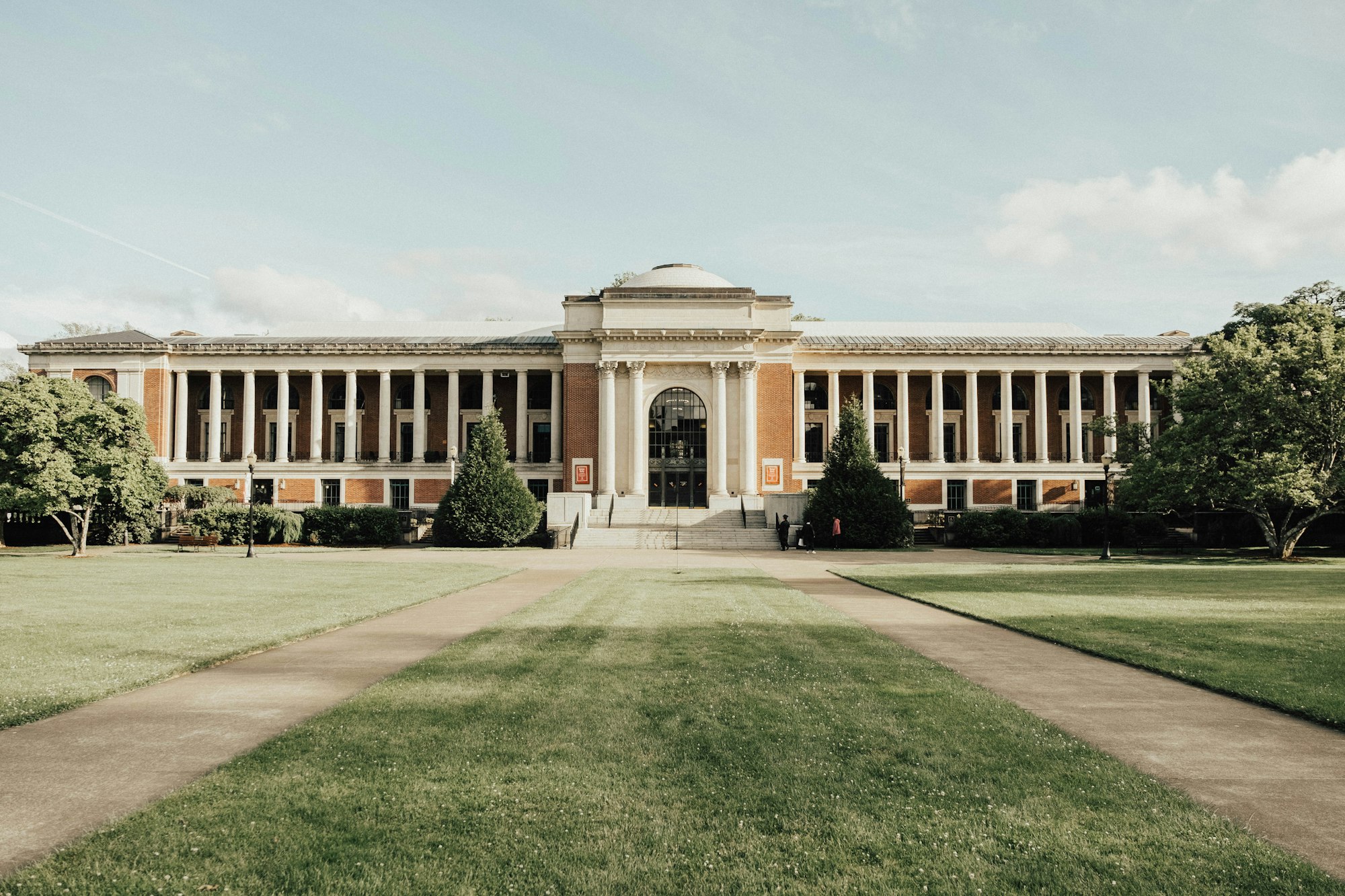 A classical red-brick academic building framed by mature trees