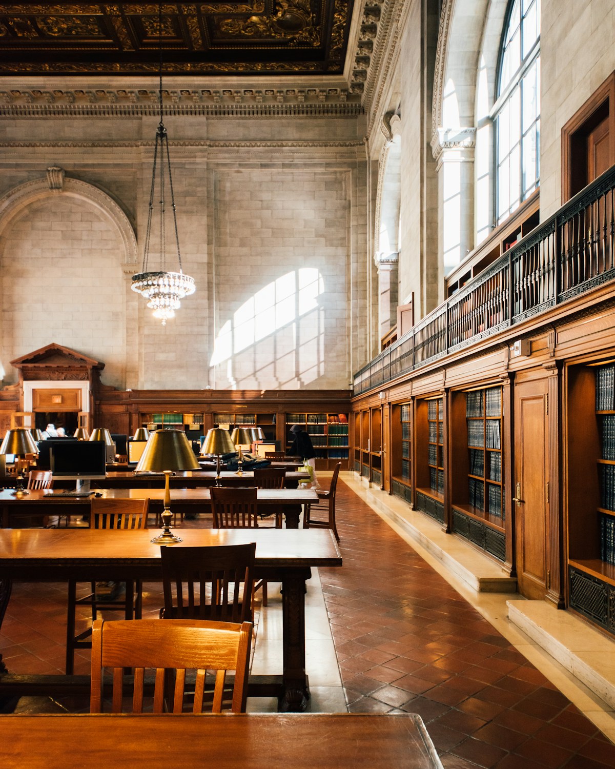 A sunlit reading room with wood bookshelves and study tables